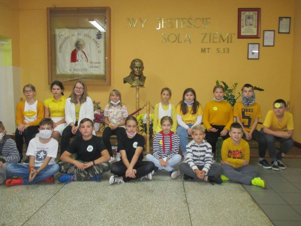 Grupa dzieci pozuje do zdjęcia na tle popiersia i obrazu Jana Pawła 2.